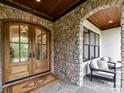 Inviting stone porch featuring double doors, stone walls, and outdoor seating at 2954 Holbrook Rd, Fort Mill, SC 29715
