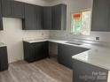 Modern kitchen with sleek, dark cabinetry, white countertops, and stainless steel sink and hardwood floors at 3137 Riber Ln, Claremont, NC 28610