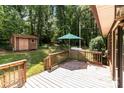 Spacious backyard featuring a wooden deck, a shed with double doors, and an umbrella for relaxing outdoors at 503 Overbrook Dr, Albemarle, NC 28001
