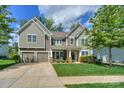 Charming two-story home featuring a manicured lawn, a two-car garage, and a welcoming front porch at 135 Canoe Pole Ln, Mooresville, NC 28117