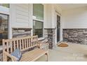 Inviting front porch with stone accents, a wooden bench, and a decorative wreath on the front door at 154 Cotton Field Dr, Statesville, NC 28677