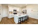 Bright kitchen with white cabinets, stainless steel appliances, a center island with bar stools, and wood-style floors at 156 Parker Claire Ln, Kings Mountain, NC 28086