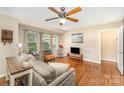 Bright living room featuring hardwood floors, a ceiling fan, comfortable seating, and multiple windows at 3529 Trent St, Charlotte, NC 28209