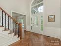Bright foyer featuring herringbone wood floors, staircase, and transom window over a glass-paneled front door at 3721 Providence Plantation Ln, Charlotte, NC 28270