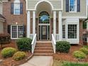 Inviting entrance with large windows above front door, columns, and landscaped bushes at 3721 Providence Plantation Ln, Charlotte, NC 28270