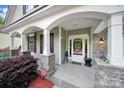Inviting covered front porch with stone columns and arched entry offers curb appeal and outdoor space at 7710 Grove Hall Ave, Mint Hill, NC 28227