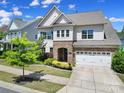 Front exterior of home with stone accents, lush landscaping, and a two-car garage on a sunny day at 1001 Emory Ln, Fort Mill, SC 29708