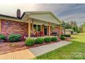 Inviting front porch with rocking chairs, decorative hanging baskets, and manicured landscaping at 1009 High Shoals Rd, Lincolnton, NC 28092