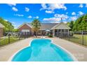 Inviting backyard with a kidney shaped pool, fenced-in yard, mature trees, and screened in porch for outdoor enjoyment at 1305 Glenview Ln, Rock Hill, SC 29730