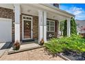 Cozy front porch featuring stone pillars, a decorative door, and manicured landscaping for curb appeal at 142 Wellshire St, Mooresville, NC 28115