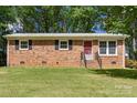 Well-kept brick home featuring a bright red front door, contrasted by green lawn and mature trees at 1975 Peace Rd, Fort Mill, SC 29715