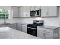 Bright kitchen featuring granite countertops, white cabinets, and stainless steel appliances at 207 Giant Oak Ave, Statesville, NC 28677