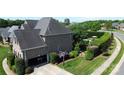 Aerial view of a brick home with an attached garage, well-maintained lawn, and a private backyard with mature trees at 3000 J R Ct, Stanley, NC 28164