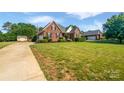 Well-manicured lawn with mature trees, a driveway, and a charming brick house at 3124 Fairmead Dr, Concord, NC 28025