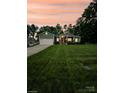 Dusk view of home's green exterior, well-kept lawn, landscaped front yard and attached garage at 414 Fulton Dr, Kings Mountain, NC 28086