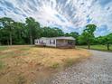 Home exterior with covered porch, surrounded by lush trees and gravel driveway at 4328 Camden Rd, Marshville, NC 28103