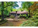 A log cabin nestled among mature trees featuring stone chimney, landscaping, and serene setting at 6510 Sharon Hills Rd, Charlotte, NC 28210