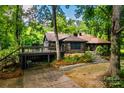 Log cabin with deck and parking featuring a natural landscape with mature trees and foliage at 6510 Sharon Hills Rd, Charlotte, NC 28210