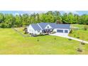 Exterior elevation of white home with 3-car garage, front porch, and meticulously landscaped front yard at 754 Culp Ferguson Rd, Lancaster, SC 29720