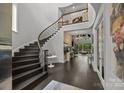 Spacious foyer with curved staircase, dark wood floors, and views into the formal living room at 10170 Enclave Cir, Concord, NC 28027