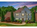 Elegant two-story home featuring a well-manicured lawn, mature trees, and a charming front entrance at 10327 Oak Pond Cir, Charlotte, NC 28277