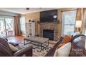 Cozy living room with stone fireplace, hardwood floors, and comfortable leather furniture at 12601 Guardhouse Ct, Charlotte, NC 28262