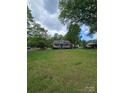 Quaint single story home from a distance surrounded by a spacious front lawn and mature shade trees at 1415 S York Rd, Gastonia, NC 28052