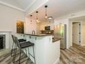 Kitchen with bar-style counter, pendant lighting, stainless steel appliances and wood floors at 233 Northwest Dr, Davidson, NC 28036