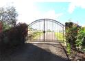Gated entrance with blooming red roses on either side, leading to a scenic driveway and property at 2530 Sharon Rd, York, SC