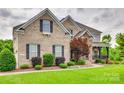 Attractive brick home features manicured landscaping, and covered porch at 308 Hollister Estates Dr, Waxhaw, NC 28173