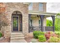 Inviting front porch features stone accents, a ceiling fan, and views of the surrounding greenery at 308 Hollister Estates Dr, Waxhaw, NC 28173