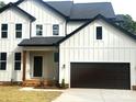 Striking two-story modern farmhouse showcasing white board and batten siding and a dark-brown two-car garage at 3114 Ansonville Rd, Marshville, NC 28103
