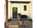 Inviting front porch with craftsman details, black front door with wreath, and a comfy bench at 3114 Ansonville Rd, Marshville, NC 28103