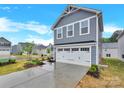 View of the two-car garage and driveway of this two-story home with gray siding and white trim at 3212 Coast Oak Rd, Charlotte, NC 28214