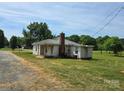 Charming single-story home with a brick chimney and a metal roof set on a spacious lot with mature trees at 5501 Barrier Rd, Concord, NC 28025