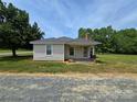 Cozy single-Gathering home exhibits a metal roof, brick chimney and a inviting front porch, all set against a serene backdrop at 5501 Barrier Rd, Concord, NC 28025