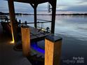 Waterfront dock featuring a covered boat slip, outdoor seating, and steps leading to the water at 578 Stonemarker Rd, Mooresville, NC 28117