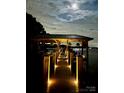 A waterfront dock featuring a covered boat slip and walkway lights under a beautiful moonlit sky at 578 Stonemarker Rd, Mooresville, NC 28117