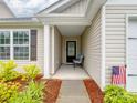 Inviting covered front porch with comfortable seating, an American flag and well-maintained landscaping at 584 Lamorak Pl, Richburg, SC 29729