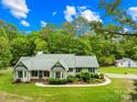 Inviting home exterior with a lush green lawn, mature trees, and charming detached garage at 5903 Wm Griffin Rd, Monroe, NC 28112