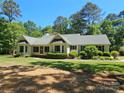 Charming single-story home featuring a well-manicured lawn, lush greenery, and a welcoming screened porch at 5903 Wm Griffin Rd, Monroe, NC 28112