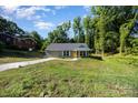 Quaint one-story home with a well-maintained lawn and a welcoming yellow front door at 611 Fernwood Dr, Albemarle, NC 28001