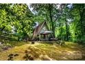 A-frame cabin exterior features a large patio area amid lush green trees at 6516 Sharon Hills Rd, Charlotte, NC 28210