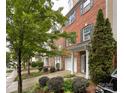 View of a brick townhome with a one-car garage and lush landscaping along the walkway, showcasing the property's curb appeal at 1295 Amber Ridge Nw Rd, Concord, NC 28027