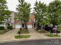 A charming brick townhome with a one-car garage, surrounded by lush landscaping, offering a warm and inviting curb appeal at 1295 Amber Ridge Nw Rd, Concord, NC 28027