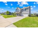 Well-manicured lawn leads to a charming two-story gray home with an attached two-car garage at 133 W Neel Ranch Rd, Mooresville, NC 28115