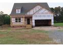 New home features a two-car garage, a covered front porch, and brick foundation detailing at 144 Mason Tanner Ct, Rock Hill, SC 29730