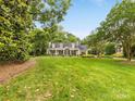 A house with a beautifully landscaped front yard and mature trees under a clear blue sky at 2611 Forest Dr, Charlotte, NC 28211