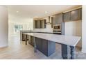 Spacious kitchen featuring a large island, gray cabinets, stainless steel appliances, and hardwood floors at 2907 W Trade St, Charlotte, NC 28208