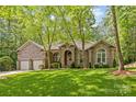 Stunning brick home featuring a two-car garage, mature trees, and manicured lawn at 4025 Cherrybrook Dr, Mint Hill, NC 28227